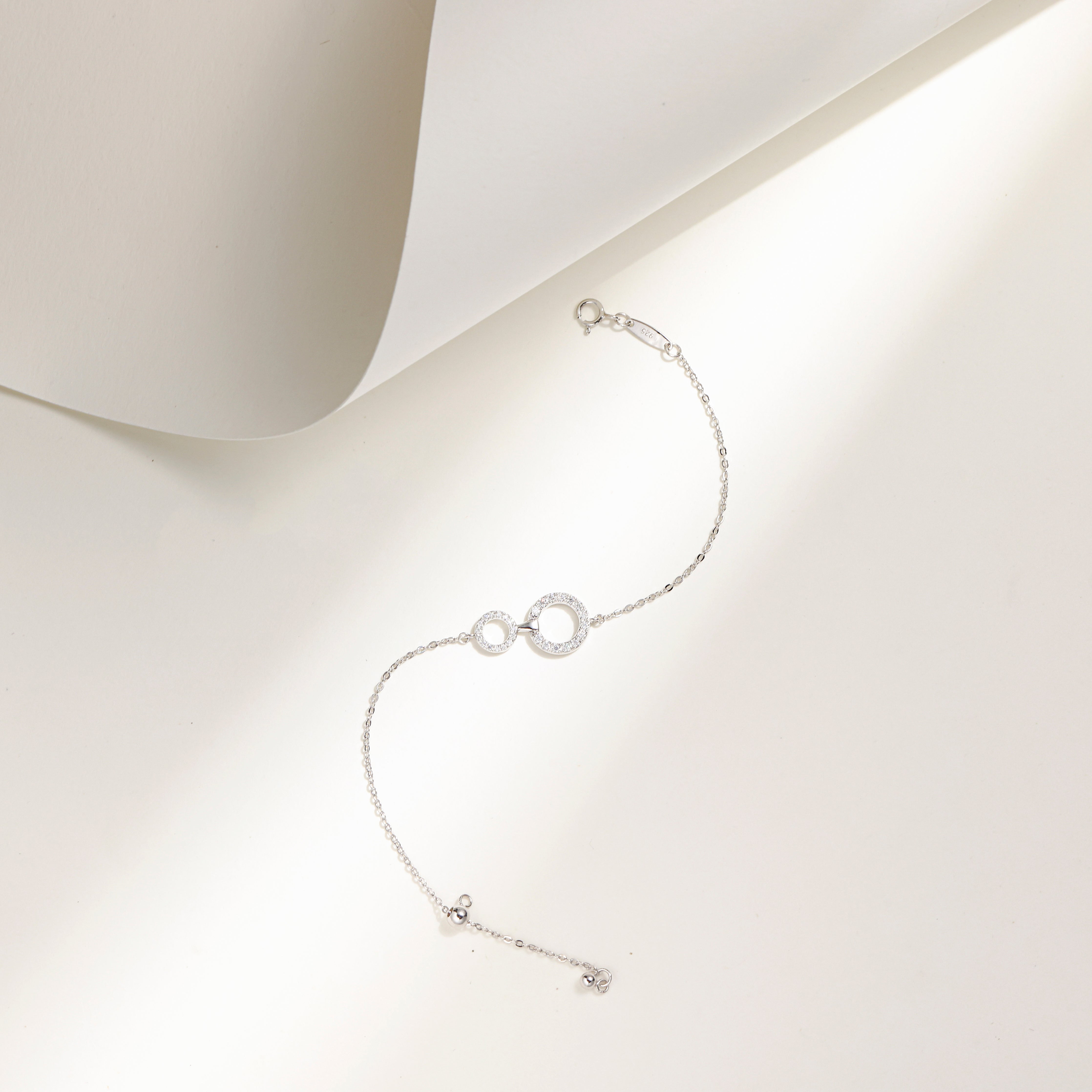 Elegant white gold plated sterling silver bracelet featuring two interlinked circles adorned with sparkling Moissanite stones and an adjustable chain.